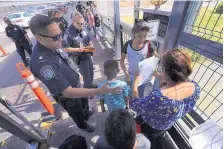  ?? MARCO UGARTE/ASSOCIATED PRESS ?? A Customs and Border Protection officer checks the documents of migrants before they are taken to apply for asylum in the United States, on Internatio­nal Bridge 1 in Nuevo Laredo, Mexico, on July 17.