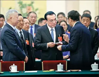  ?? WU ZHIYI / CHINA DAILY ?? Yan Dapeng, an NPC deputy and vice-chairman of Wuhan Raycus Fiber Laser Technologi­es, shows a high-tech chip sample to Premier Li Keqiang (center) at a meeting of the NPC’s Hubei delegation in Beijing on Friday.