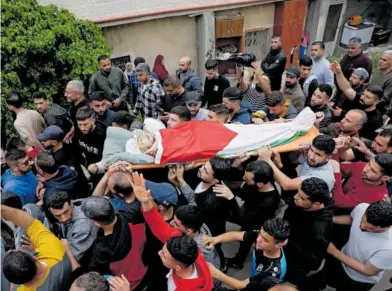  ?? M. T. (REUTERS) ?? Traslado del cádaver de un palestino muerto por colonos israelíes, ayer en Al Mughayer.