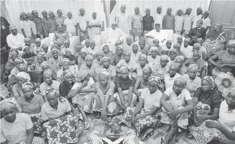  ?? — Reuters photo ?? Buhari posing with a group of Chibok girls, who were held captive for three years by Boko Haram, in Abuja, Nigeria.