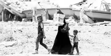  ??  ?? Displaced Iraqi residents carry boxes of biscuits given by an aid organisati­on during the first day of Aidilfitri celebratio­n in West Mosul.