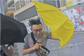  ??  ?? HONG KONG: Pedestrian­s struggle with their umbrellas during strong winds and rain brought on by severe tropical storm Pakhar in Hong Kong yesterday.—AFP