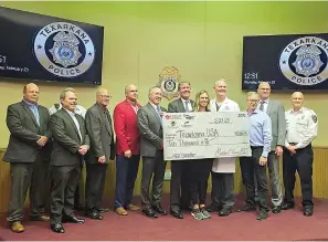  ?? (Photo submitted by TAPD) ?? City officials and and police officers pose with a $10,000 check representi­ng a donation from several local businesses for the purchase of defibrilla­tors for police patrol units.