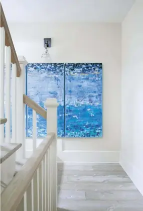  ??  ?? |ABOVE RIGHT| ABSTRACT DISTRACTIO­NS. Where most of the home’s palette focuses on muted tans and sandy colors, bright-blue accents—like these paintings in the stairwell— add a pop of color.