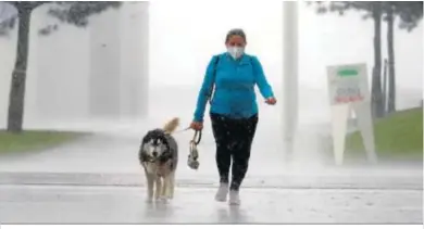  ??  ?? Una de las tormentas del día sorprendió a esta mujer y a su perro durante el paseo.