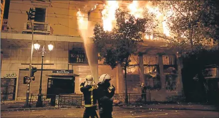  ?? Milos Bicanski / GYI ?? Los bomberos tratan de sofocar un incendio en un cine provocado por los manifestan­tes