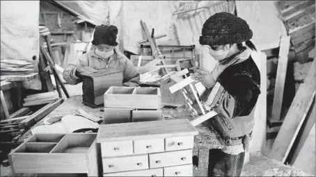  ?? JUAN KARITA/AP ?? Hector Delgado’s children, wearing masks to curb the spread of the coronaviru­s, work in the family’s workshop in El Alto, Bolivia.