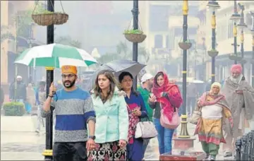  ?? SAMEER SEHGAL/HT ?? Visitors amid the drizzle on Heritage Street in Amritsar on a cold Tuesday.