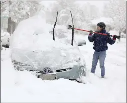  ?? KRISTIN MURPHY — THE DESERET NEWS VIA AP ?? Cathy Morgan-Mace cleans snow and ice off her family's car during a snowstorm in Salt Lake City, Utah, on Wednesday.