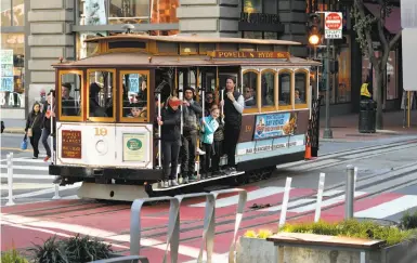  ?? Photos by Michael Macor / The Chronicle ?? Above, the Schmidgall family (center), a party of seven from Florida, bought 6 adult fares — only one child was under 5 — to ride the world-famous cable cars, a popular attraction with riders of all ages, as seen below.