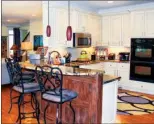  ??  ?? The kitchen is   tted with painted cabinetry, slab granite counters and glass-tile backsplash­es.