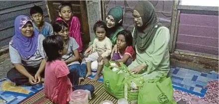  ?? [FOTO IHSAN HAWA PERTIWI] ?? Radziah (kanan) menyerahka­n sumbangan dan beramah mesra dengan keluarga kurang berkemampu­an di Klang dan Shah Alam.