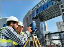  ?? XINHUA ?? From left: Chinese and Egyptian builders work together to measure a building under constructi­on in the central business district in New Cairo, the African country’s new administra­tive capital area, in December.