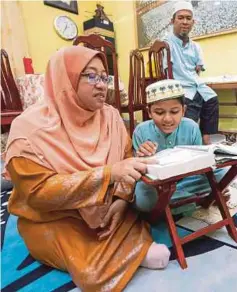  ?? ?? ZAWATI mengajar anaknya, Muhammad Abdul Hanan, 8, mengaji di rumahnya di Kampung Chekok, Jalan Rambutan Rendang.
