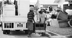  ??  ?? Men remove an item of discarded furniture from the yard of a Greenvale Park. (Photo: Trinidad Guardian)