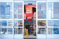  ?? THE ASSOCIATED PRESS ?? A woman carries items while the sliding doors begin to close on a Toys R Us location during a liquidatio­n sale Friday in Elizabeth, N.J. Toys R Us is opening its doors with a going-out-of-business sale, offering clearance discounts at all 735 stores,...