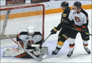  ?? PERRY BERGSON/THE BRANDON SUN) ?? Medicine Hat Tigers goalie Mads Søgaard makes a save as Brandon Wheat Kings forward Luka Burzan and Tigers defenceman Dylan MacPherson battle in front of the net in Brandon Tuesday.