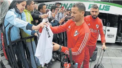  ?? PRENSA RIVER ?? Rodrigo Mora firma camisetas en el arribo de River a Bogotá, Detrás, Lucas Pratto.