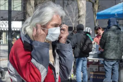  ?? The Canadian Press ?? Stewart Greville dons a mask as he waits for volunteers giving food and aid to the homeless on Friday in Montreal.