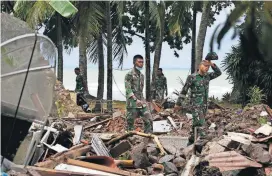  ?? [AP PHOTO] ?? An Indonesian soldier walks near debris Wednesday at a tsunami-ravaged area in Carita, Indonesia.