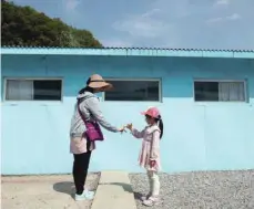  ?? — Reuters ?? A girl and woman gesture to make a promise over a cement block symbolisin­g a border line as they mimic a handshake between North Korean leader Kim Jong Un and South Korean President Moon Jae-in at the summit in April, at the replica of the truce village of Panmunjom at a movie studio in Namyangju.