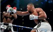  ?? PHOTO: REUTERS ?? Anthony Joshua, right, has Carlos Takam on the ropes in Cardiff as he defends his heavyweigh­t titles.