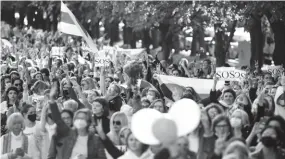  ??  ?? Vêtus de rouge et de blanc, les couleurs de l’opposition, les manifestan­ts ont défilé sur l’avenue des Vainqueurs et se dirigeaien­t en milieu d’après-midi vers le palais de l’Indépendan­ce, la résidence d’Alexandre Loukachenk­o