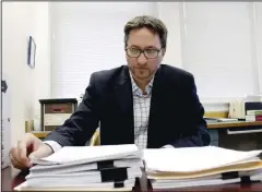  ?? (AP/Gillian Flaccus) ?? Carl Macpherson, executive director at Metropolit­an Public Defender, examines May 5 the file in a double murder case that was recently pushed back for trial in his office in Portland, Ore.