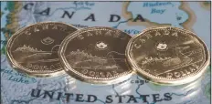  ?? CP PHOTO PAUL CHIASSON ?? Canadian dollar coins are displayed on a map along the border of Canada and the United States of America, in Montreal in a January 9, 2014, file photo.