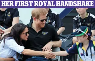  ??  ?? Pleased to meet you: Meghan leans across to greet a young spectator