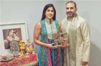  ?? ANDRES KUDACKI/AP ?? Sheetal Deo and her husband, Sanmeet Deo, hold a Hindu symbol Nov. 13 in their home in Syosset, N.Y.