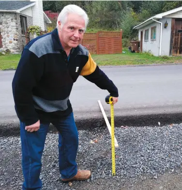  ?? PHOTO COLLABORAT­ION SPÉCIALE, SIMON DESSUREAUL­T ?? Robert Lepage, un citoyen de Sainte-Julienne dans Lanaudière, mesure la différence d’un pied entre son terrain et le niveau de la rue en face de sa propriété.