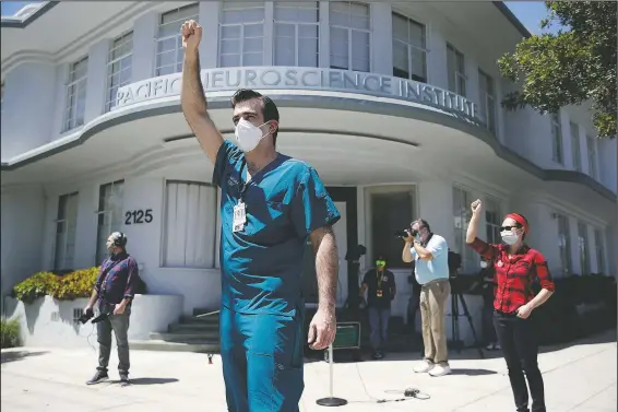  ?? (File photo/AP/Marcio Jose Sanchez) ?? n c g t s ’ Nurses Michael Gulick (center) and Angela Gatdula (right) hold their arms up in protest in April outside of Providence Saint John’s Health Center in Santa Monica, Calif. The hospital suspended 10 nurses, including Gulick, from their jobs the previous week after they refused to care for covid-19 patients without being provided protective N95 face masks. Gatdula says she contracted covid-19 and has recovered.
