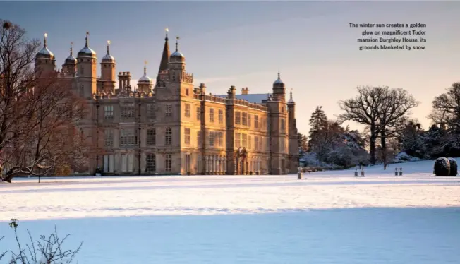  ??  ?? The winter sun creates a golden glow on magnificen­t Tudor mansion Burghley House, its grounds blanketed by snow.