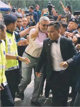  ??  ?? ... Shah Alam MP Khalid Samad being led away after a group believed to be supporters of Pasir Salak MP Datuk Seri Tajuddin Abdul Rahman tried to attack him. Khalid had been involved in a spat with Tajuddin, who is Agricultur­e and Agro-based Industry...