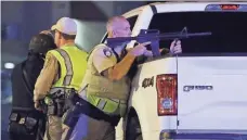  ?? JOHN LOCHER, AP ?? A police officer takes cover behind a truck during the chaos that took place near the Mandalay Bay on Sunday.