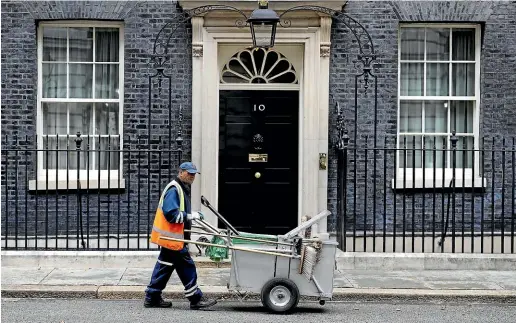  ??  ?? A street cleaner works outside No. 10 Downing Street, while inside Prime Minister Boris Johnson plans an exit from the EU regardless of British politics.