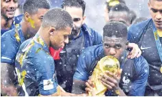  ?? — AFP photo ?? France’s Kylian Mbappe (left) holds the World Cup trophy as Samuel Umtiti kisses it after winning the Russia 2018 World Cup final.