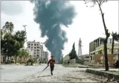  ?? HASAN MOHAMED/AFP ?? A child runs along a street in front of clouds of smoke billowing following a reported airstrike on Douma, the main town of Syria’s rebel enclave of Eastern Ghouta, on March 20.
