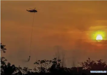  ?? Photos: Xinhua ?? Helicopter tries to extinguish fire in Kampar, Indonesia ... A water bombing helicopter tries to extinguish a fire in Kampar, Riau, Indonesia, on October 6, 2019.