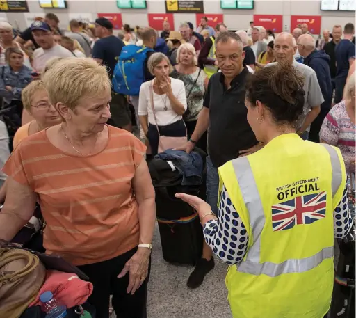  ?? Pictures: GEOFF ROBINSON, AFP ?? A British official speaks to passengers at Palma de Mallorca Airport in Spain yesterday as chaos reigns after Thomas Cook’s collapse