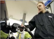  ??  ?? Attendant James Lewis pumps gas Wednesday at a station in Portland, Ore.