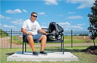  ?? [BRYAN TERRY/ THE OKLAHOMAN] ?? Cashion assistant coach Cale Cochran and his 2-month-old son, Jaxon, listen to music while sitting on a bench dedicated to his late wife, Jacie Cochran, earlier this season. Jacie died during childbirth on July 2. Now, Cale and Jaxon sit on that bench each home game talking to Jacie.