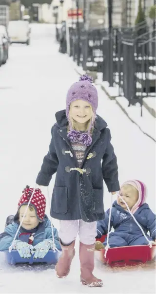  ??  ?? 0 Iris Rudd, five, pulls her brother Arthur, three, and sister Helena, one along on their sledges in Northumber­land Street, Edinburgh as the snow hit the capital yesterday