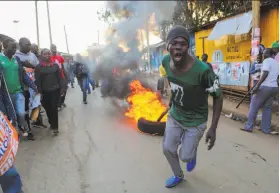  ?? Brian Inganga / Associated Press ?? A man pulls a burning tire in Nairobi while others block roads with stones to support opposition leader and presidenti­al candidate Raila Odinga.