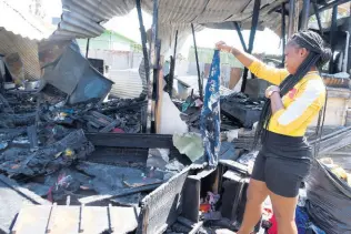  ?? PHOTOS BY KENYON HEMANS/PHOTOGRAPH­ER ?? A woman salvages what she can from charred rubble on Tuesday after fire destroyed a home on the Old Harbour main road the night before. Conroy Houston, 61, perished in the blaze.