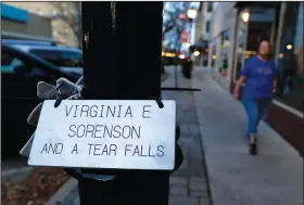  ?? (AP/Martha Irvine) ?? A plaque honoring Virginia “Ginny” Sorenson rests on a lamp post Nov. 3 along Main Street in Waukesha, Wis., as Donna Kalik walks nearby. Sorenson was a leader and member of the Milwaukee Dancing Grannies who was killed when the driver of an SUV sped through a Christmas parade in Waukesha last November, killing six and injuring dozens of other people.