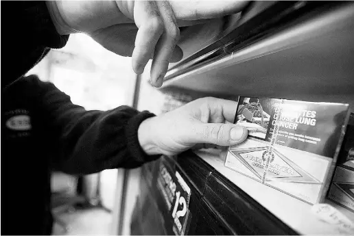  ?? GEOFF ROBINS / AFP / Gett y Imag es files ?? A corner store owner in St. Thomas, Ont., with a package of cigarettes.