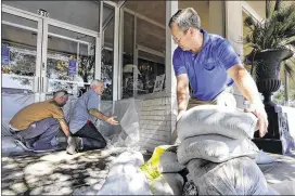  ?? MIC SMITH / ASSOCIATED PRESS ?? Jay Ashby (from left), Scott Youngblood and Frazer Eades prepare furniture store Augustus &amp; Carolina with plastic and sandbags in the coastal community of Georgetown, S.C., on Thursday. Gov. Nikki Haley warned residents of low-lying areas near the coast to prepare for a second round of flooding.