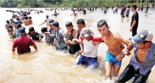  ?? Reuters ?? Migrants make a human chain in a river between Guatemala to Mexico in Ciudad Hidalgo on Monday. WASHINGTON: